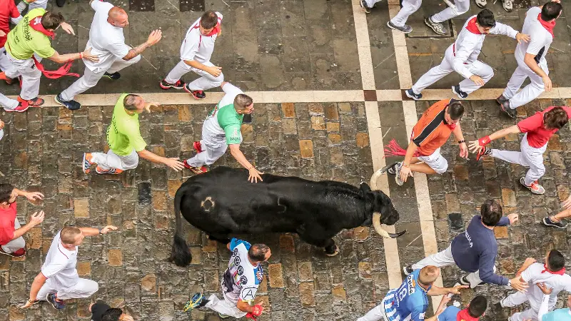 Los corredores se abren alrededor de un toro, fotografiados desde arriba (2018).