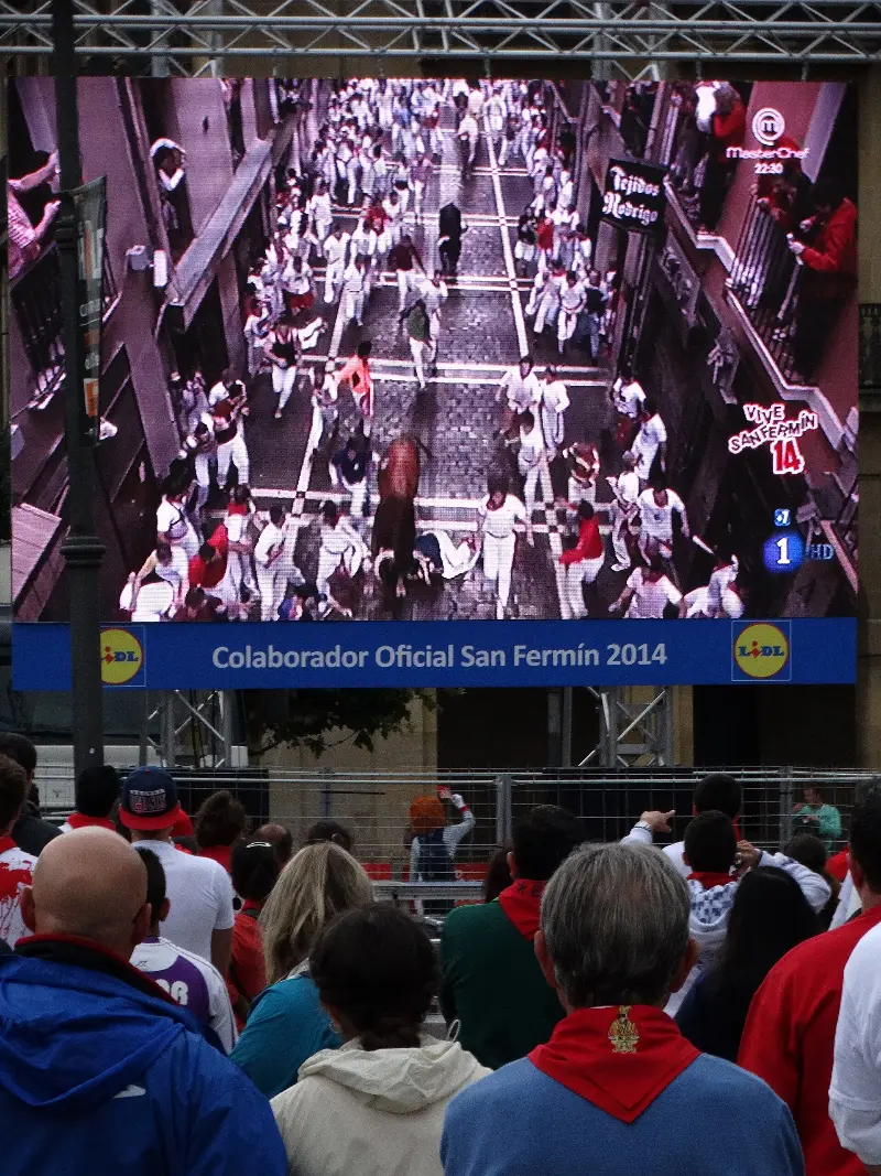 Vecinos viendo la repetición del encierro de la mañana en una pantalla (2014).