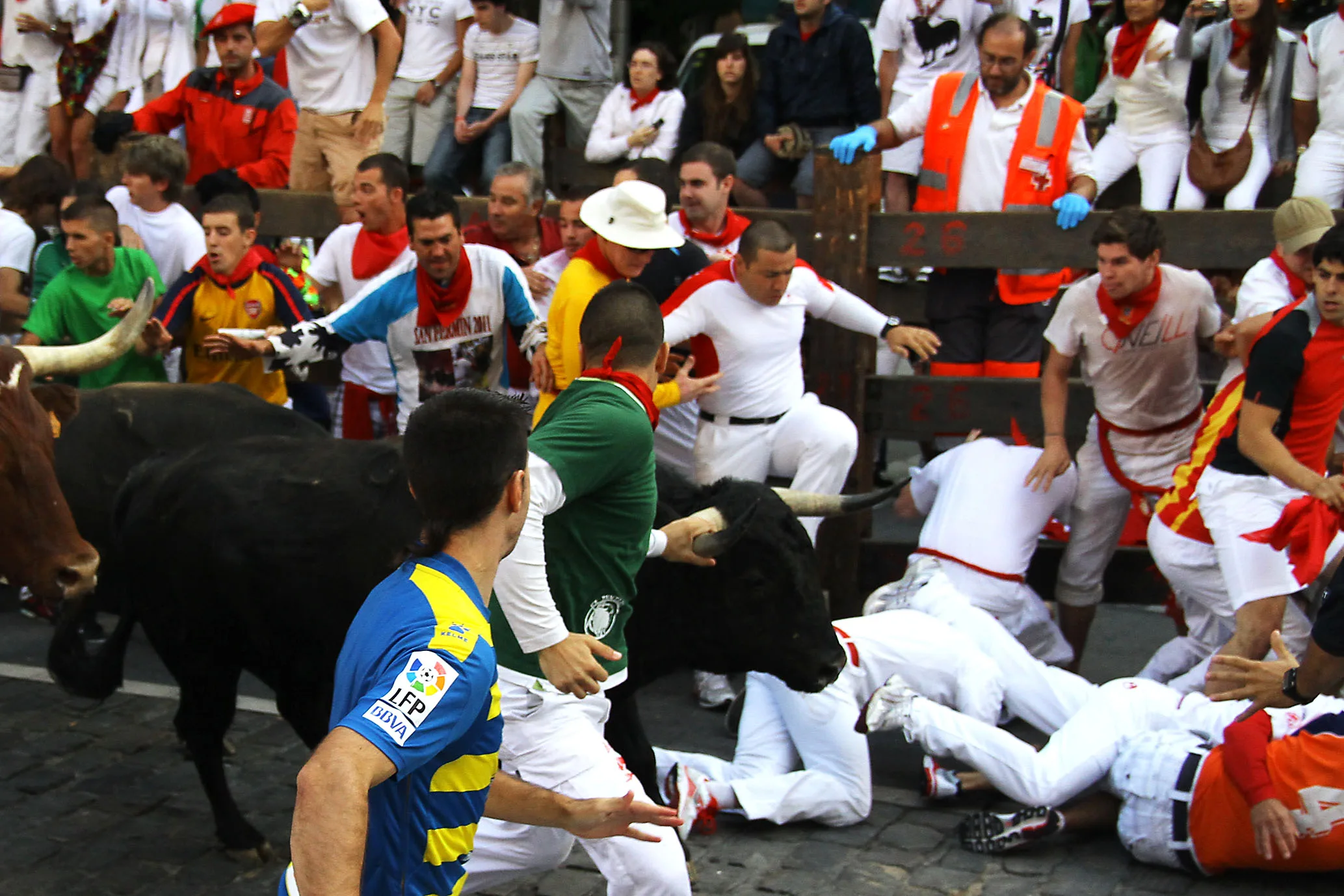 Corredores caídos en un montón mientras se acercan los toros en el encierro de Pamplona